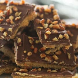 A plate of chocolate toffee bars topped with chopped nuts.