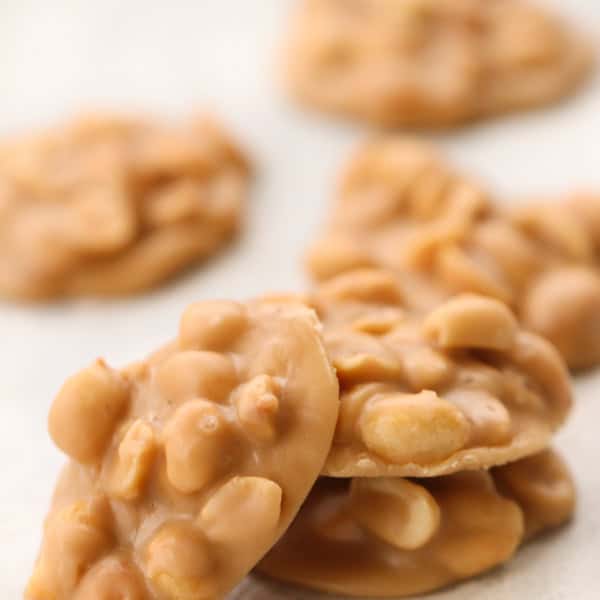 Close-up of several pieces of peanut brittle arranged on a light-colored surface.