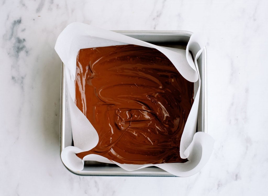 A layer of melted chocolate in a square pan lined with wax paper.