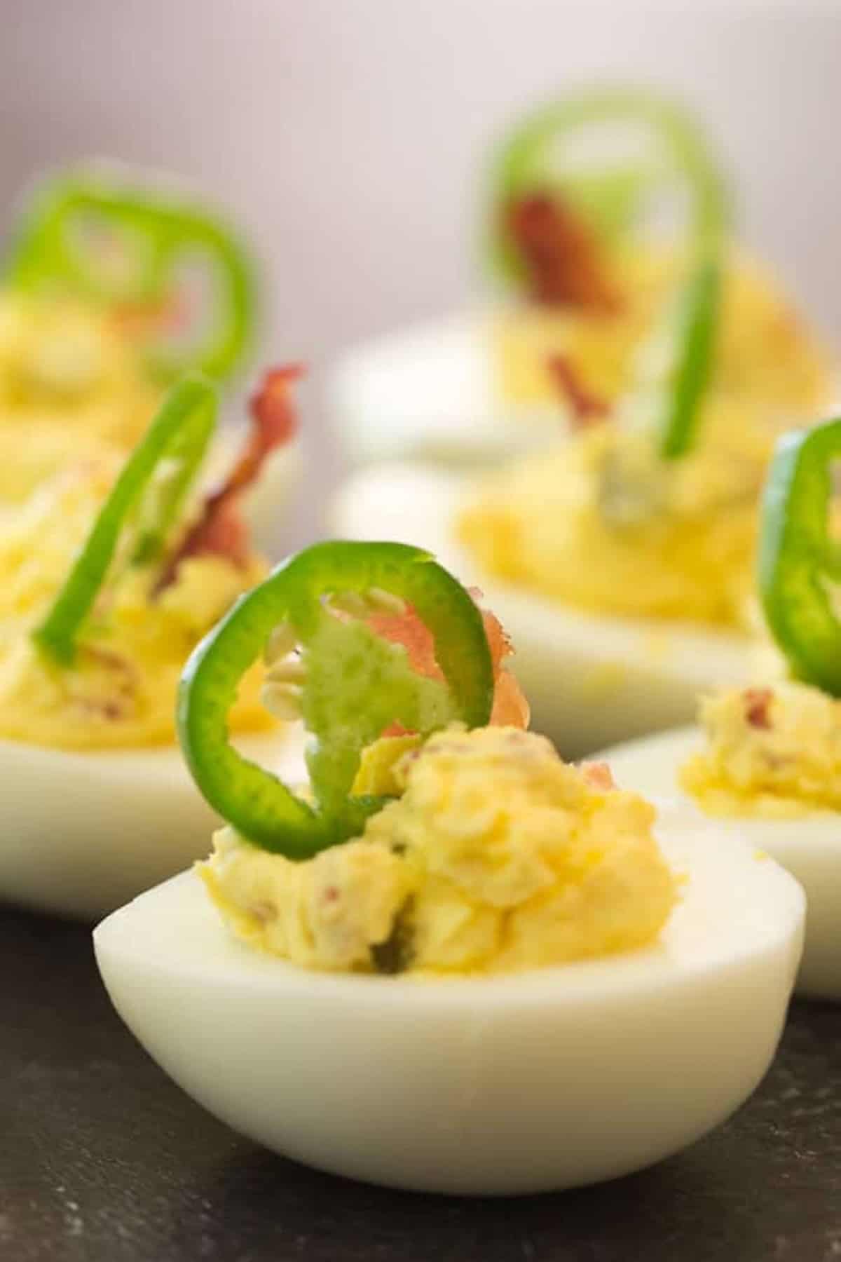 Close-up of deviled eggs garnished with sliced jalapeños.