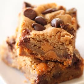 Two stacked pieces of chocolate chip blondies on a white plate.