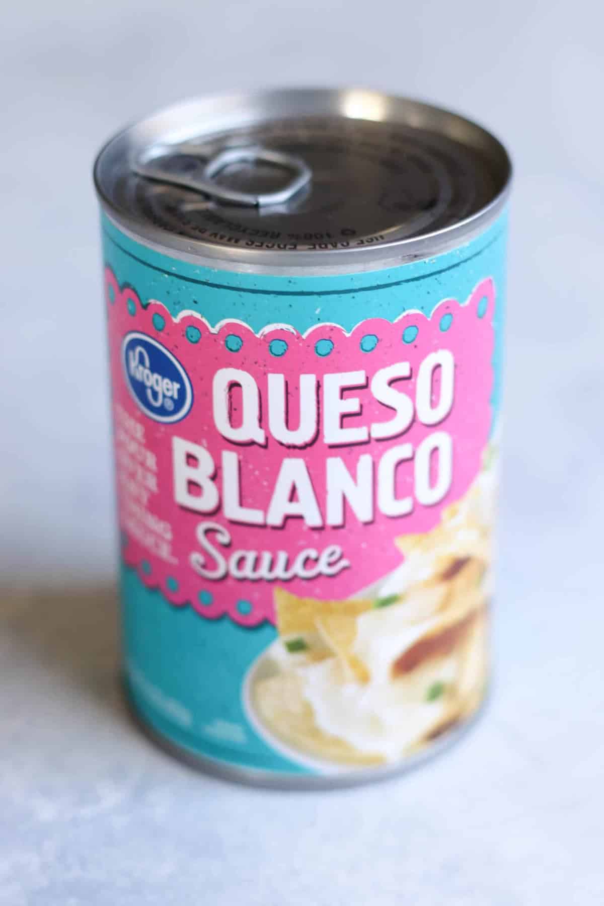 A can of Kroger Queso Blanco sauce with a blue and pink label, showing an image of cheese sauce with chips.