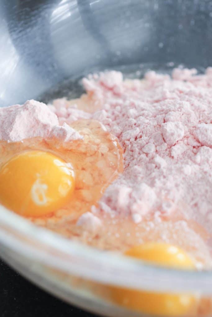 Strawberry cake mix, eggs and oil in a glass mixing bowl.