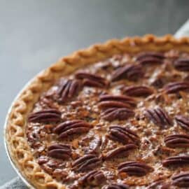 A freshly baked pecan pie with a golden crust on a checkered cloth surface.