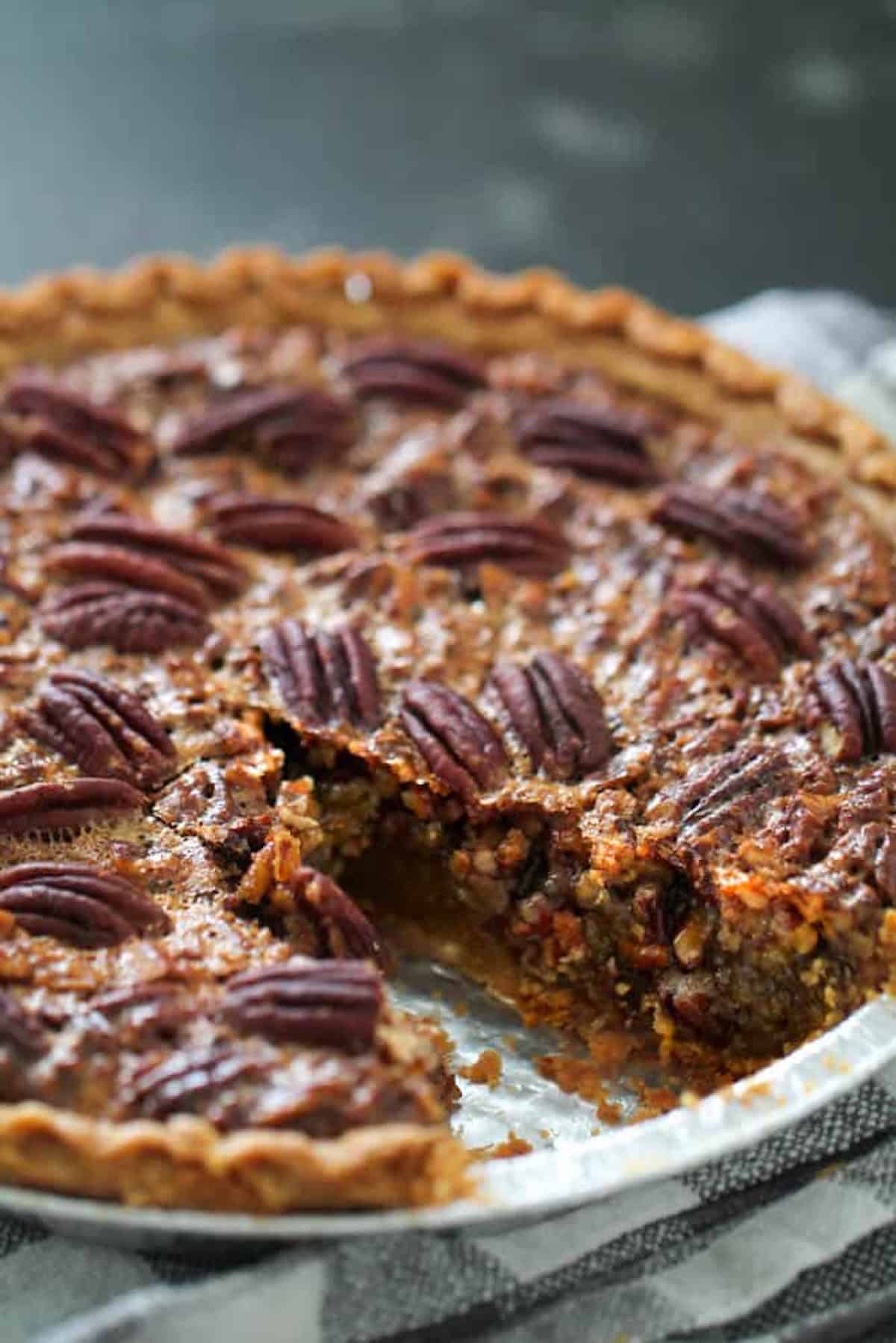 Pecan pie with a slice removed, showing a rich filling and decorative pecans on top.