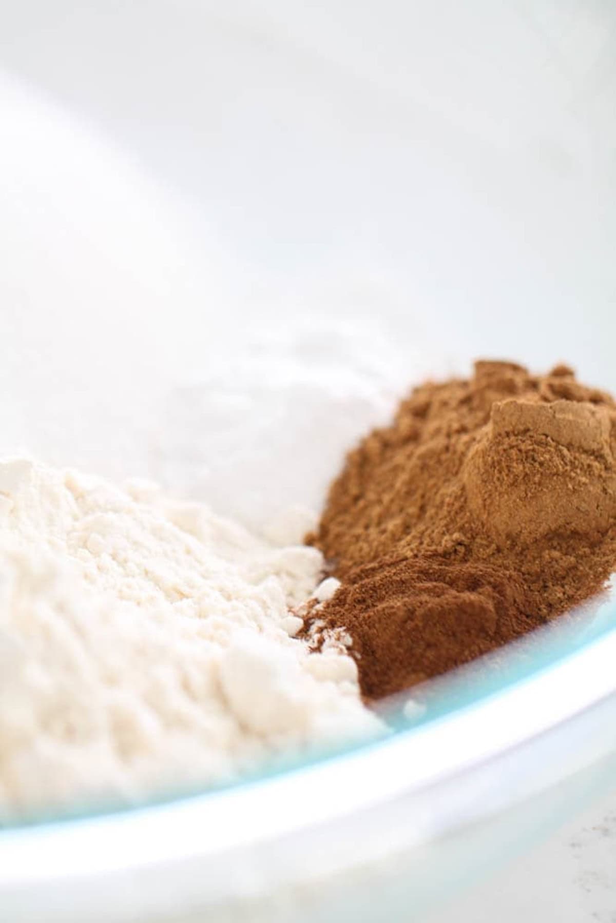 Close-up of a mixing bowl with flour and cinnamon placed next to each other.