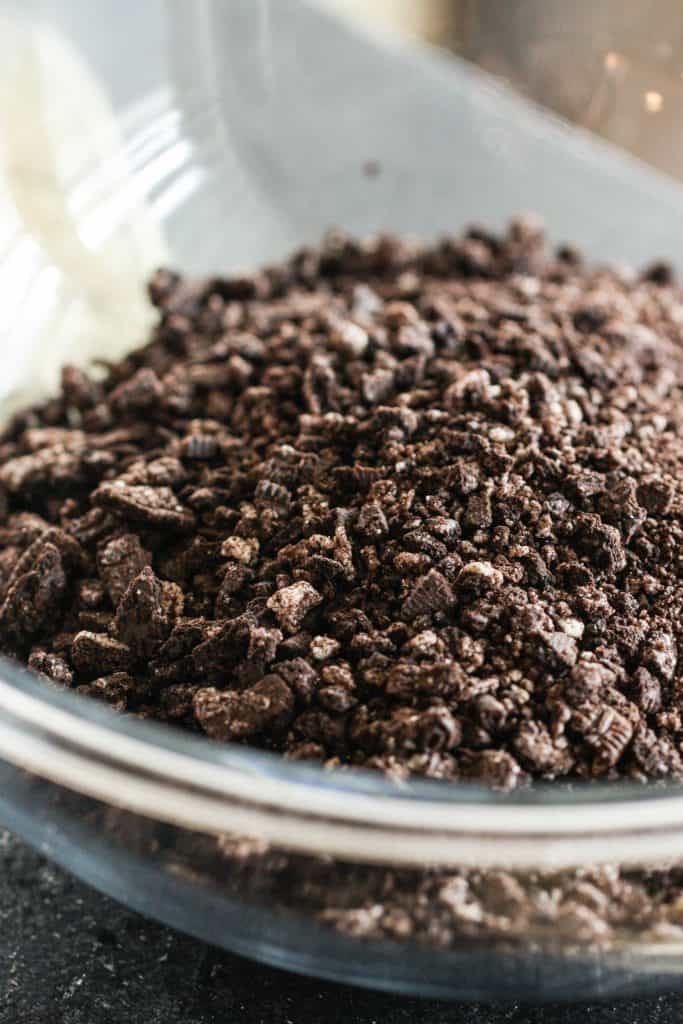 A glass mixing bowl full of oreo crumbs.