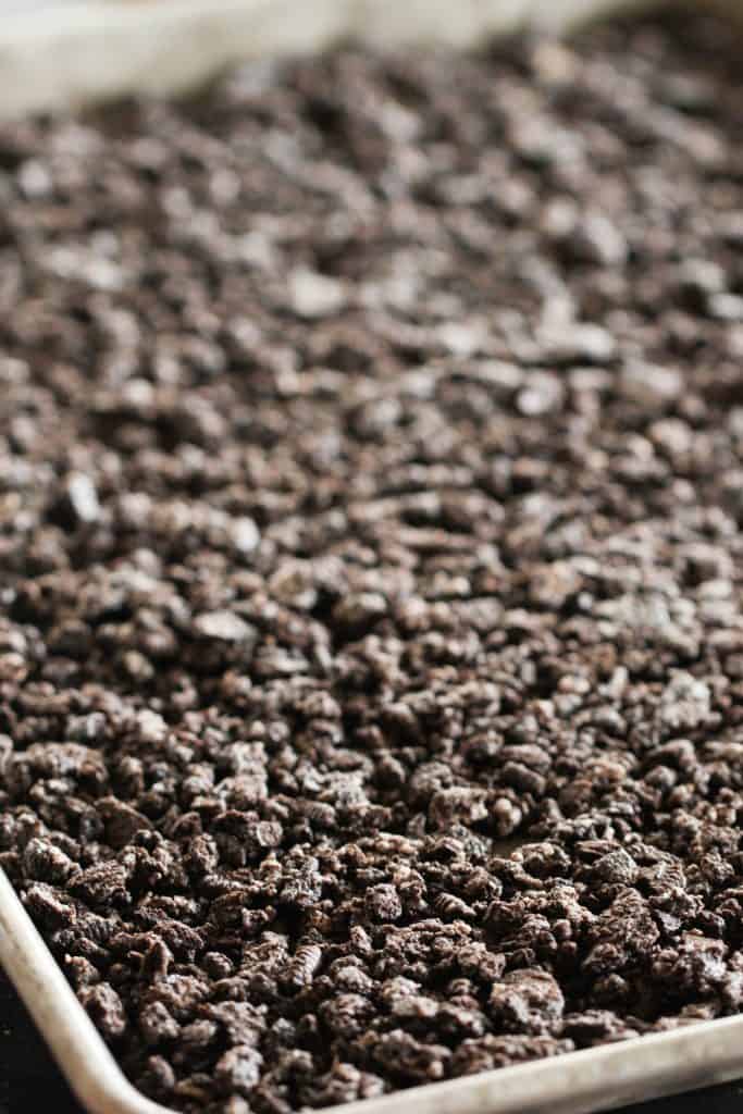 Oreo crumb mixture pressed into a baking sheet to create a crust.