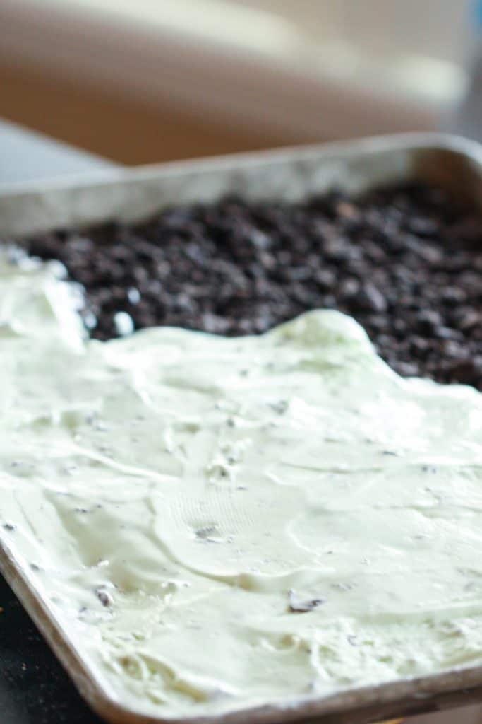 Spreading softened mint ice cream on top of oreo crust.