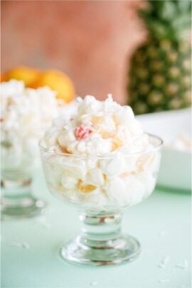 A glass filled with a serving of Easy Ambrosia Salad. With other glasses with servings in the background.