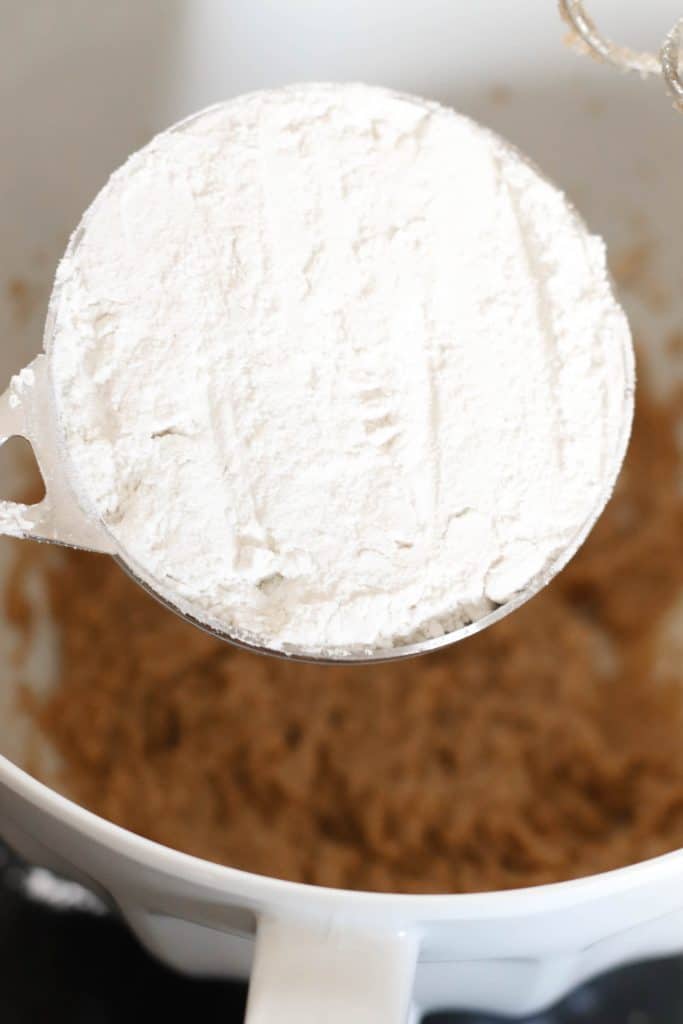 Cup of flour held above edible batter in bowl.