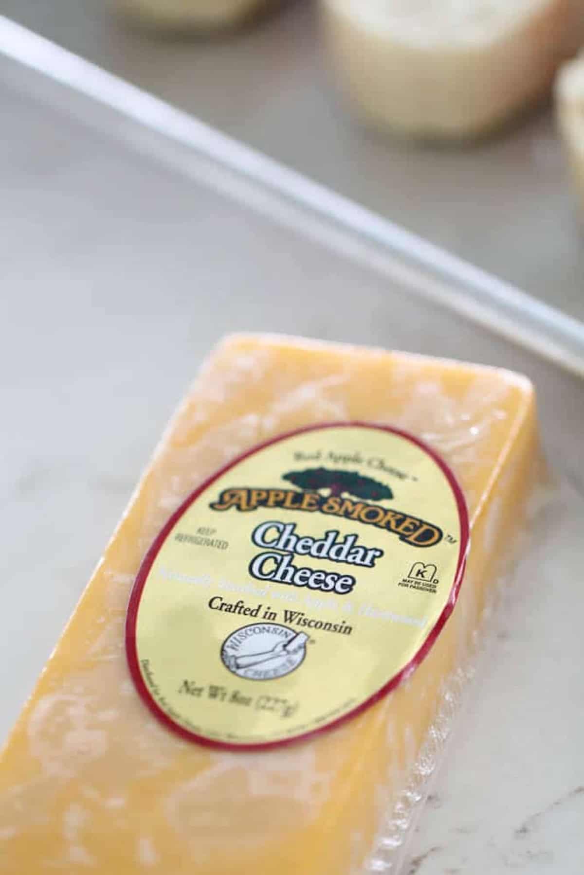 A block of apple smoked cheddar cheese from Wisconsin, wrapped in packaging with a label.