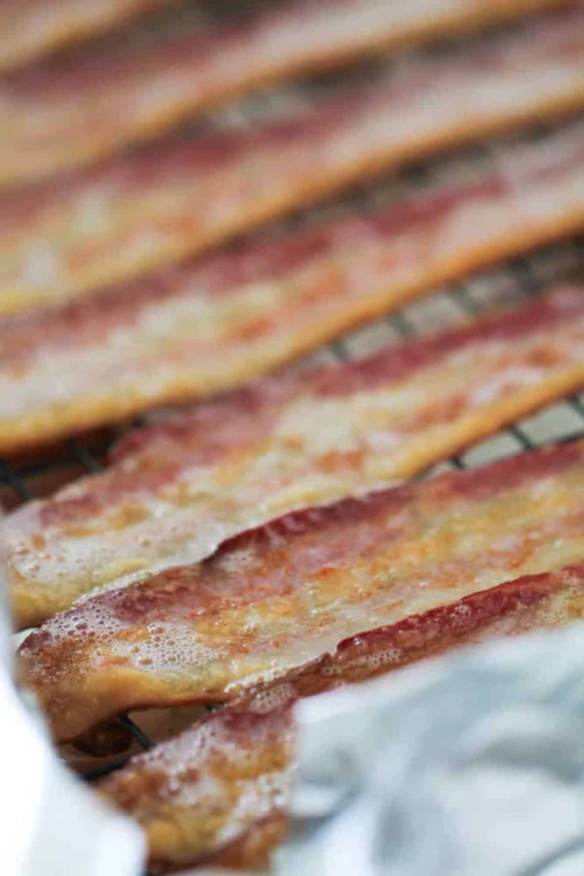 Close-up of several strips of cooked bacon on a wire rack.