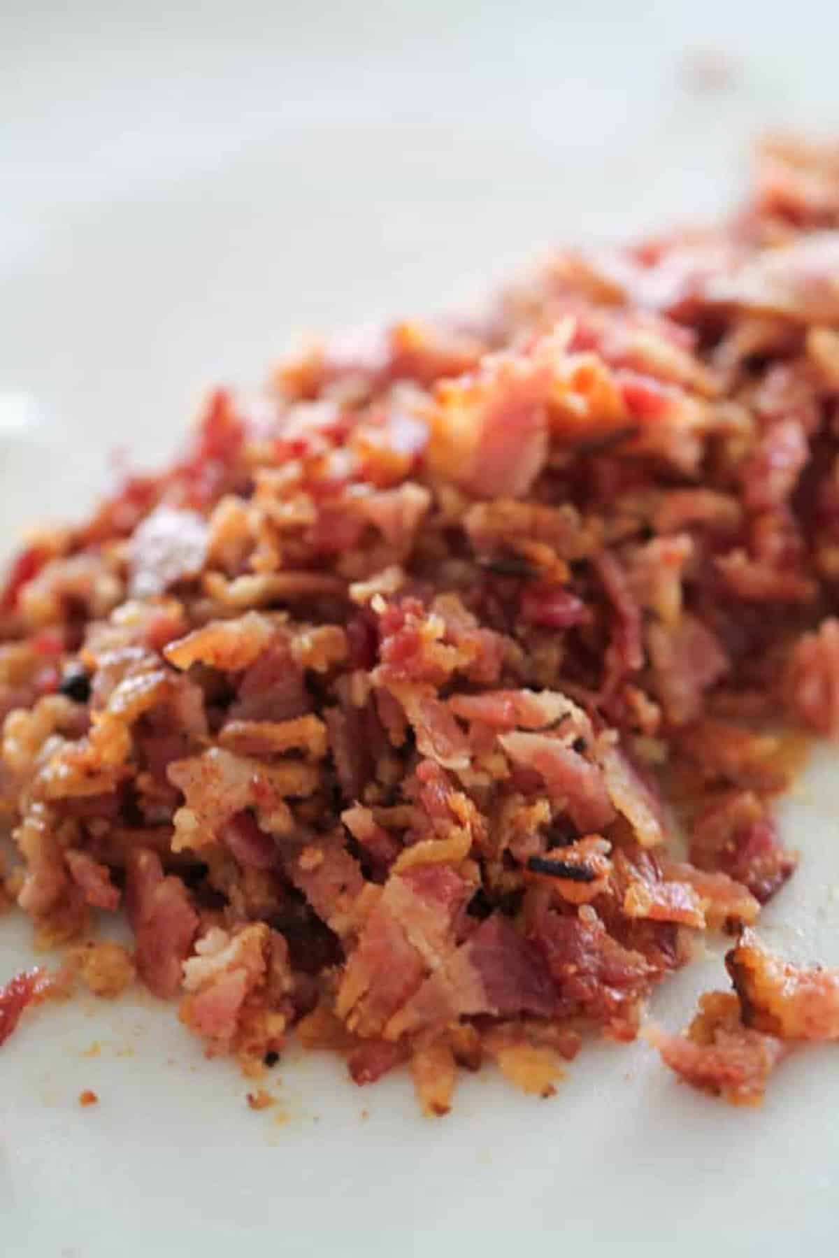 A pile of chopped, cooked bacon on a light-colored surface.