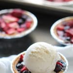 Mini Berry Pies on a table with one topped with ice cream.