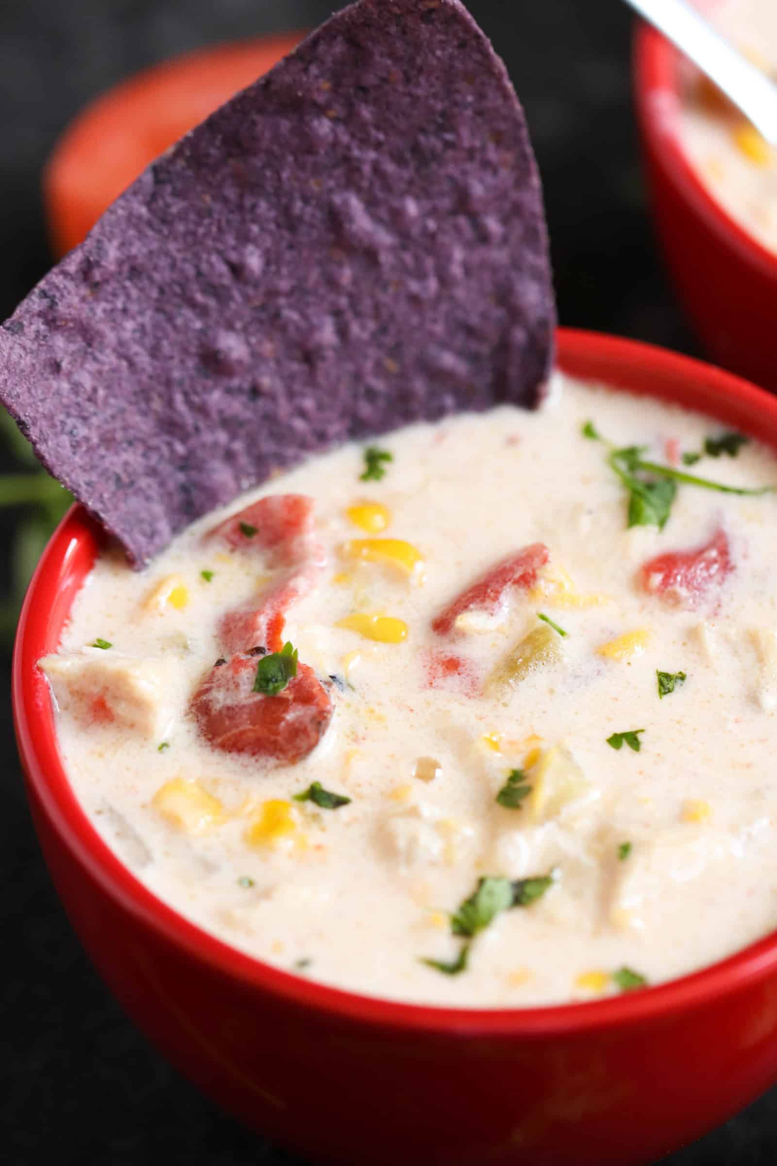 white cheddar corn chowder in a bowl with a purple tortilla cookie