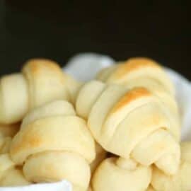 A basket filled with freshly baked dinner rolls on a white cloth.