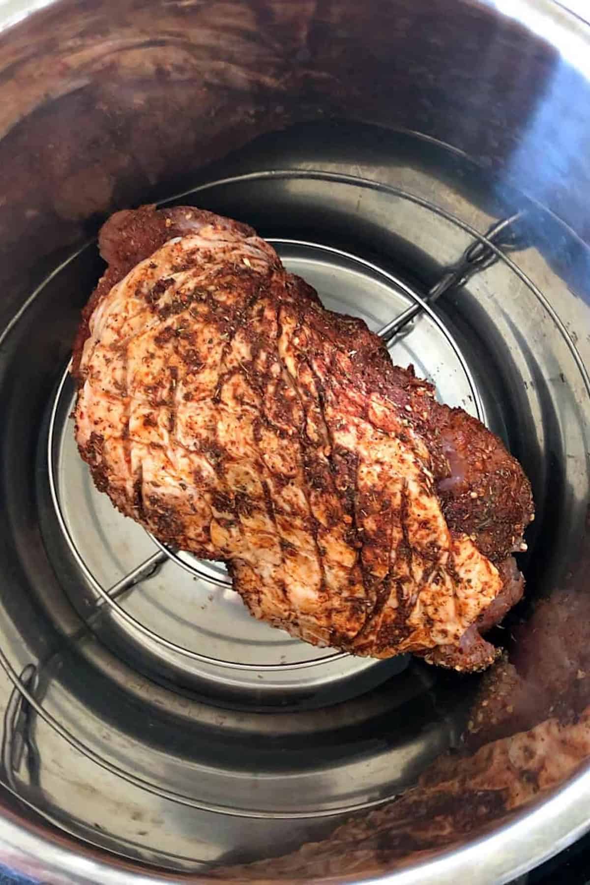 A seasoned turkey breast sits on a rack inside an Instant Pot, ready for cooking.