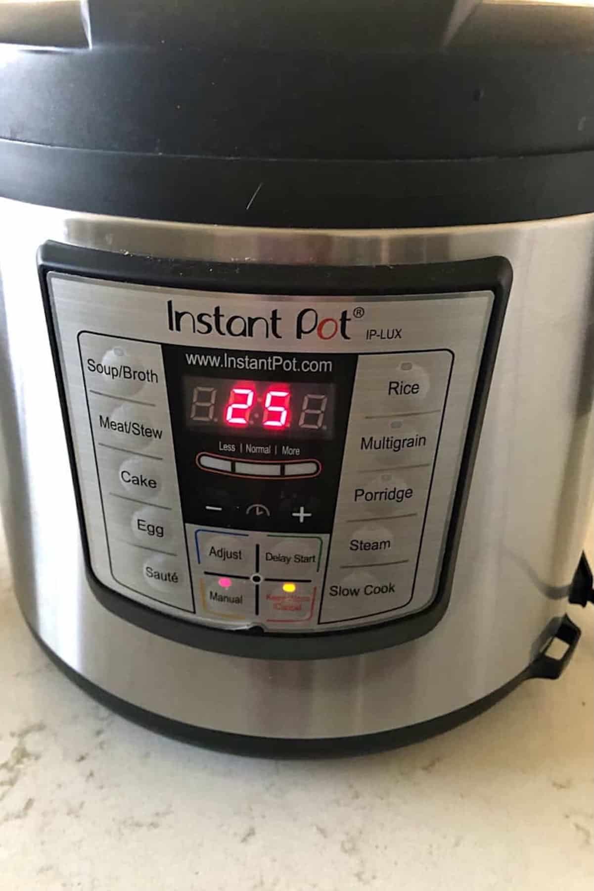 Close-up of an Instant Pot with a digital display showing 25 minutes. The control panel includes various cooking modes such as Soup/Broth, Meat/Stew, Cake, Rice, Multigrain, and more.