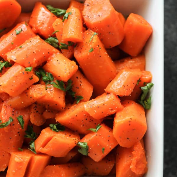 Diced cooked carrots seasoned with herbs and pepper, served in a white rectangular dish.