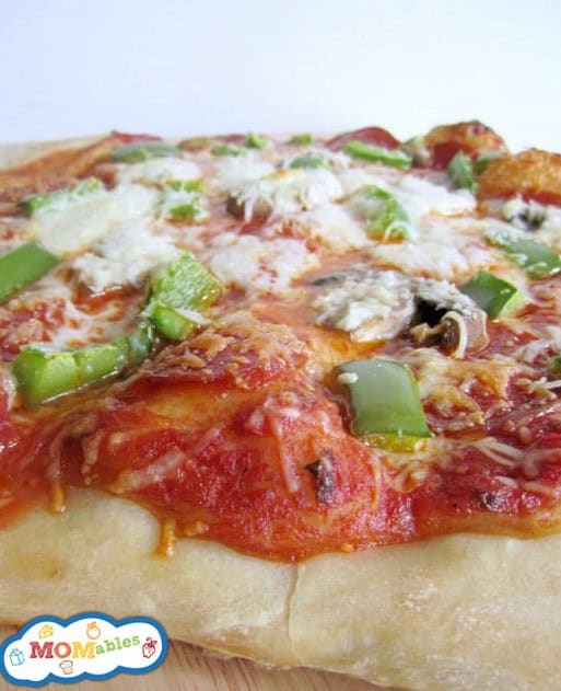 A close-up view of a homemade pizza topped with green bell peppers, mushrooms, and melted cheese.
