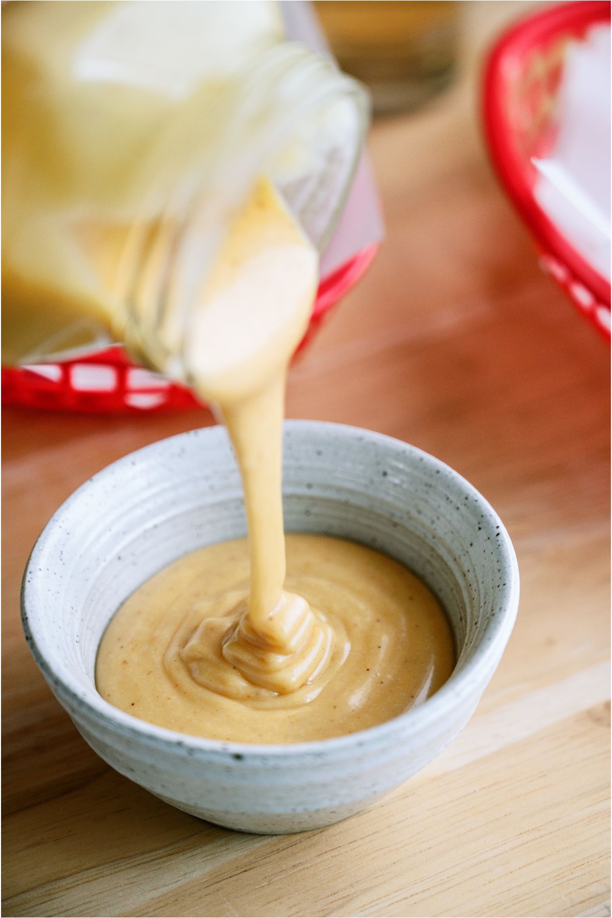 Pouring Copycat Chick-Fil-A Sauce from a jar into a serving bowl.