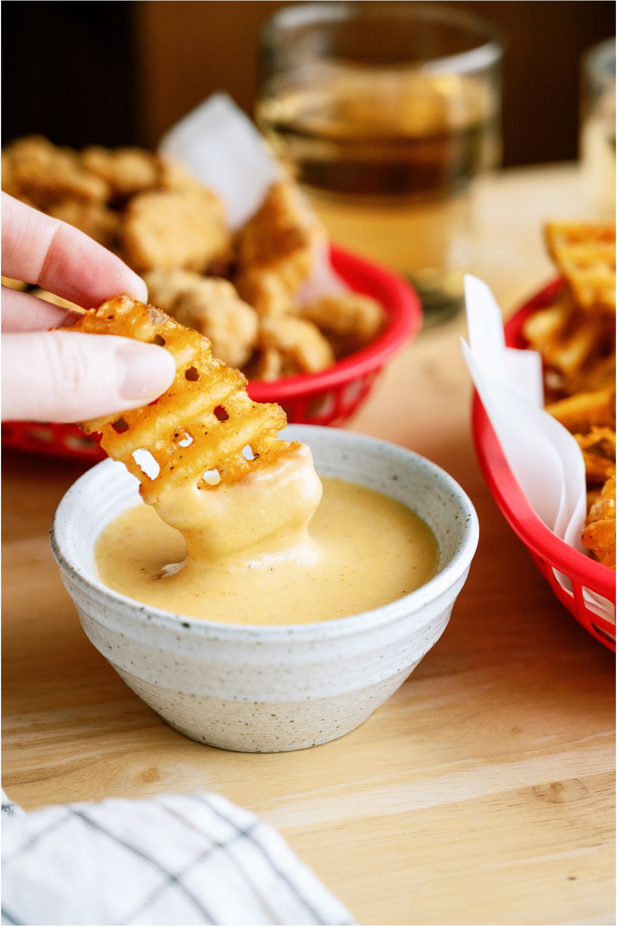 A hand dipping a french fry into a bowl of Copycat Chick-Fil-A Sauce.