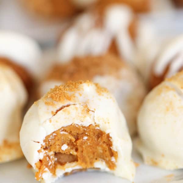 Close-up view of partially bitten dessert balls covered in white chocolate with a caramel-colored filling.