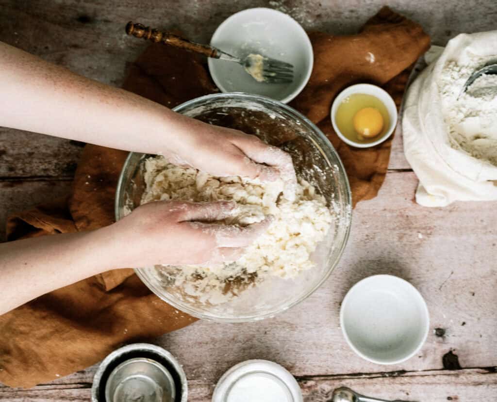 Mixing together ingredients in glass mixing bowl by hand to make a pie crust.