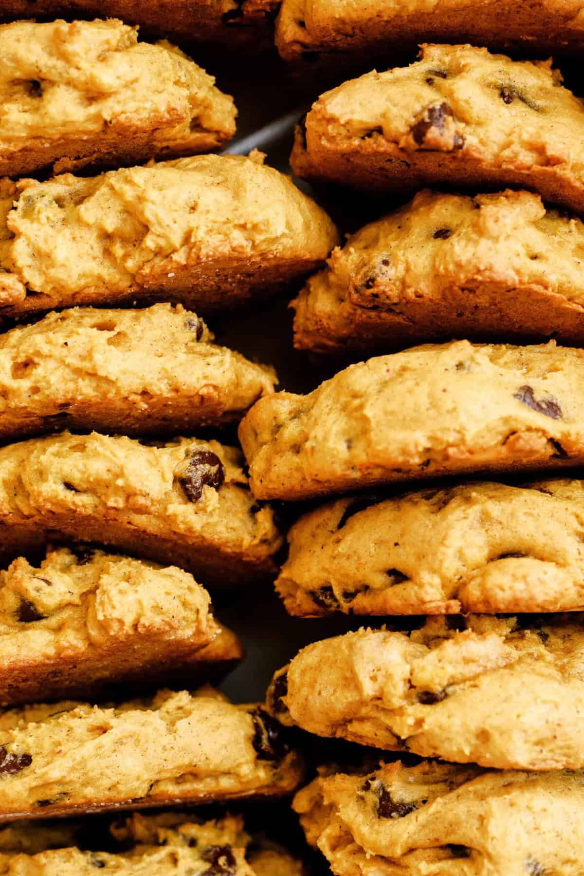 Close-up view of several freshly baked pumpkin chocolate chip cookies stacked on top of each other.