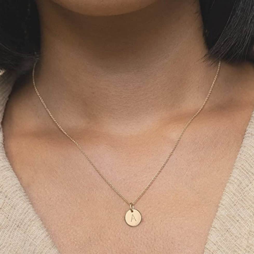 simple gold monogram necklace on a woman