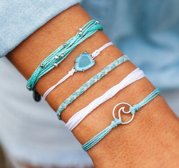 five blue and white bracelets on a women\'s wrist