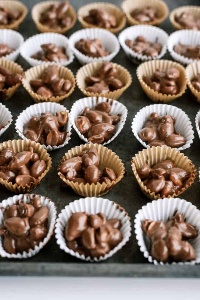 Chocolate clusters inside cupcake liners on a baking sheet.