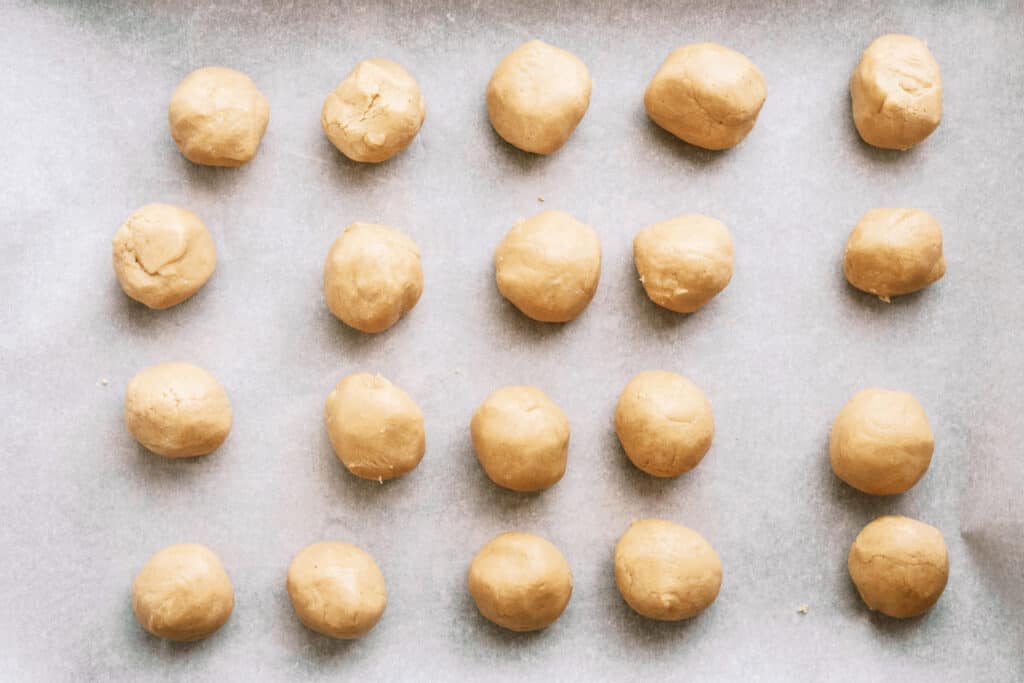 A baking sheet with rows of peanut butter dough balls.