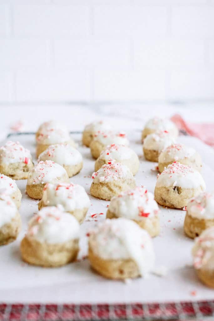 Several Peppermint Snowball Cookies grouped together on a cooling rack covered with parchment paper.