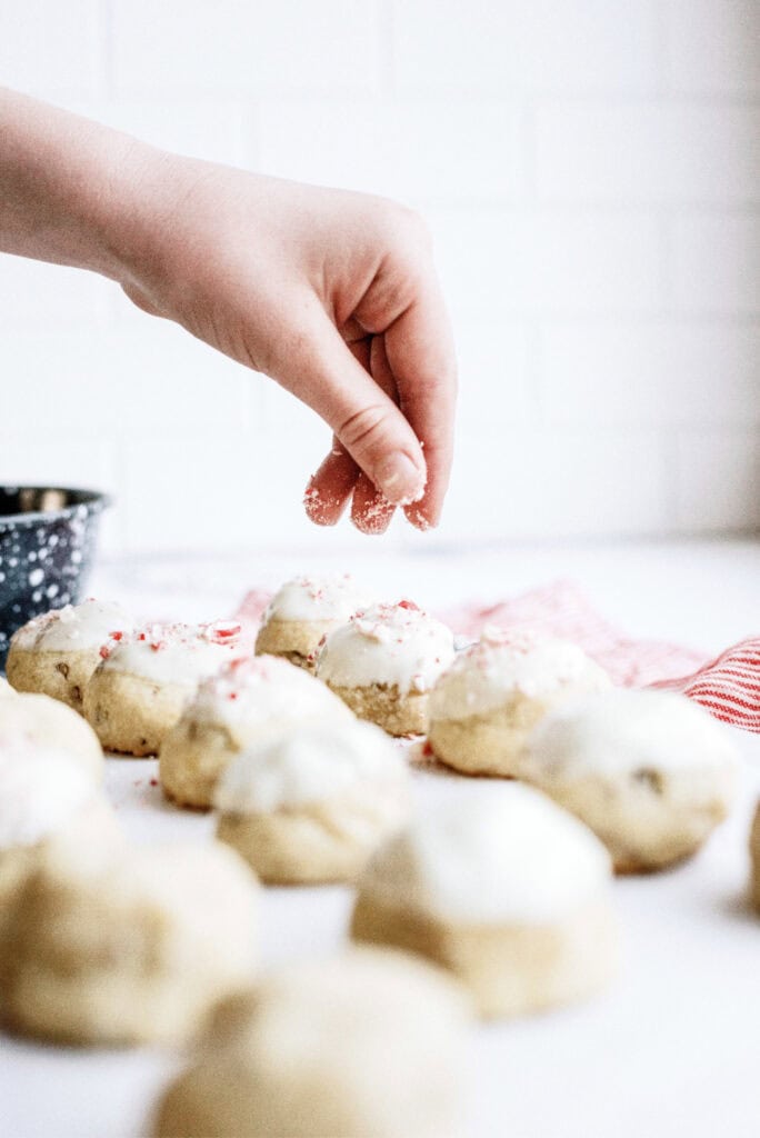 Sprinkling crushed candy canes on top of dipped cookies.