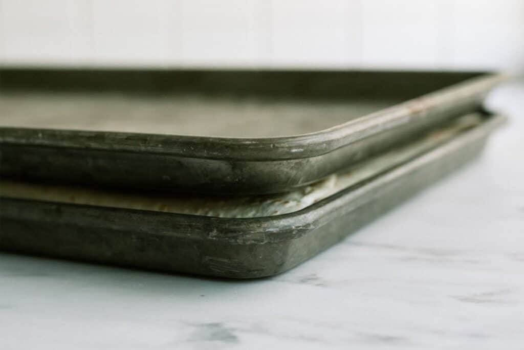 Stacked metal baking trays on a light kitchen counter.