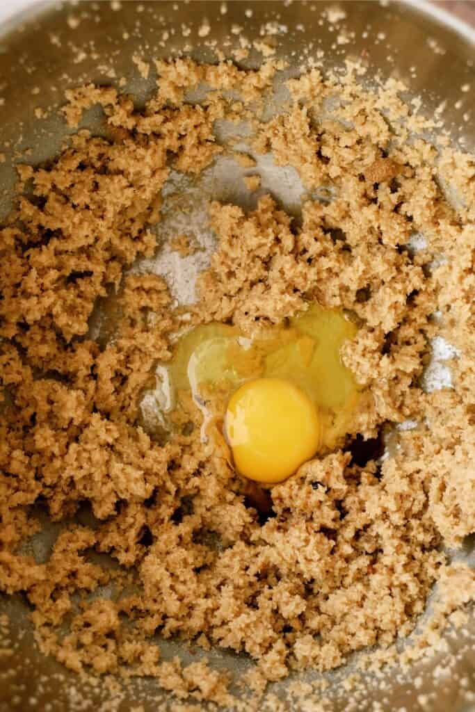 Adding eggs to dough mixture in mixing bowl.