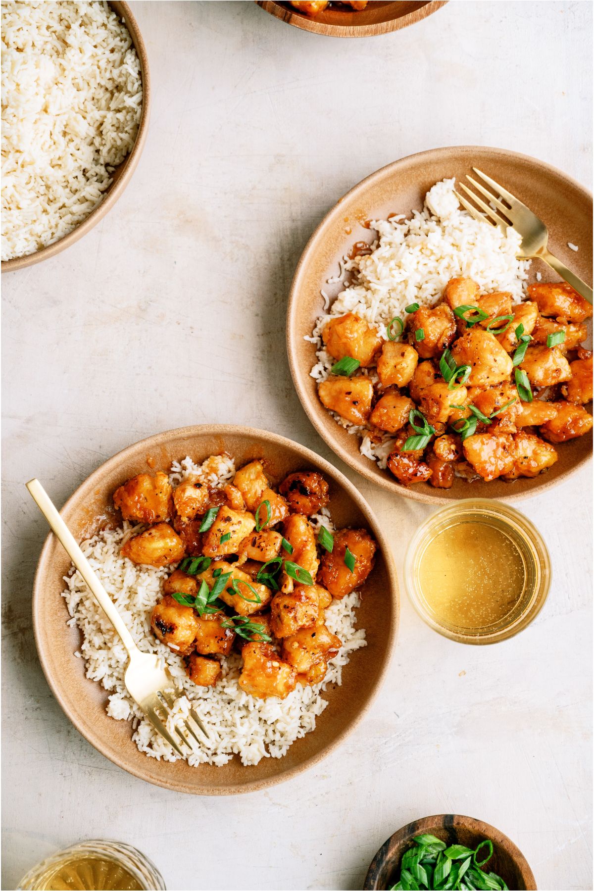 Top view of 2 plates of Baked Sweet and Sour Chicken served over white rice with forks.