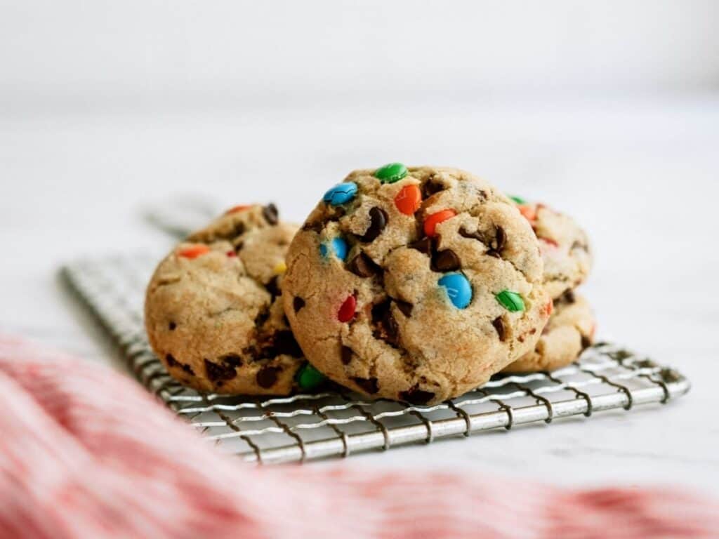 Close up of stacked M&M Cookies on a cooling rack.