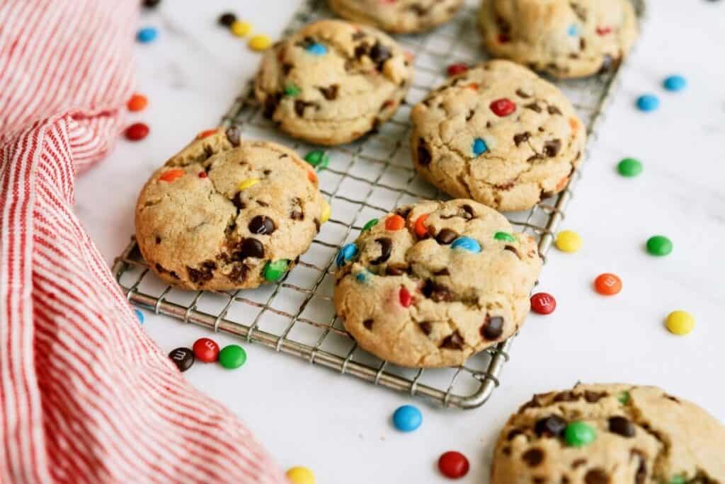 M&M Cookies on a cooling rack surrounded by mini M&M's.