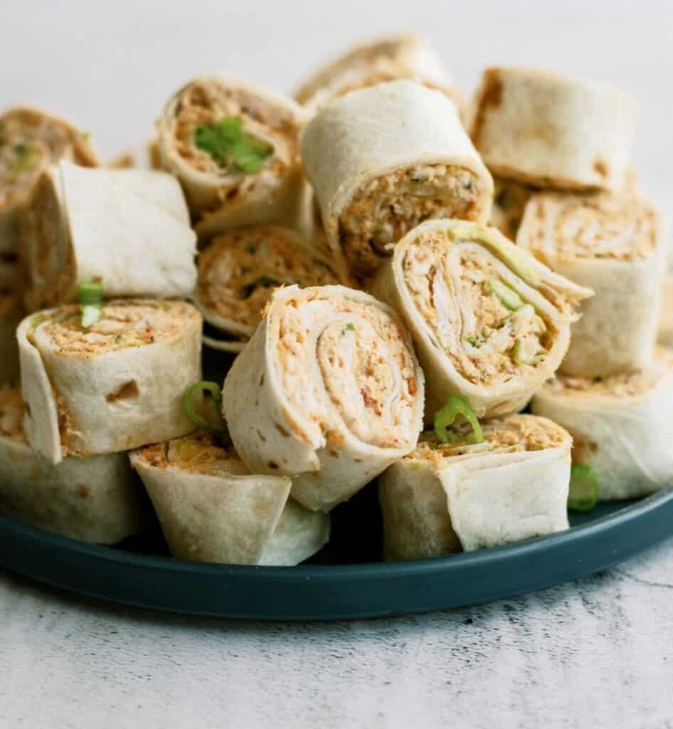 A plate of tortilla pinwheels filled with a creamy mixture, garnished with green onions.