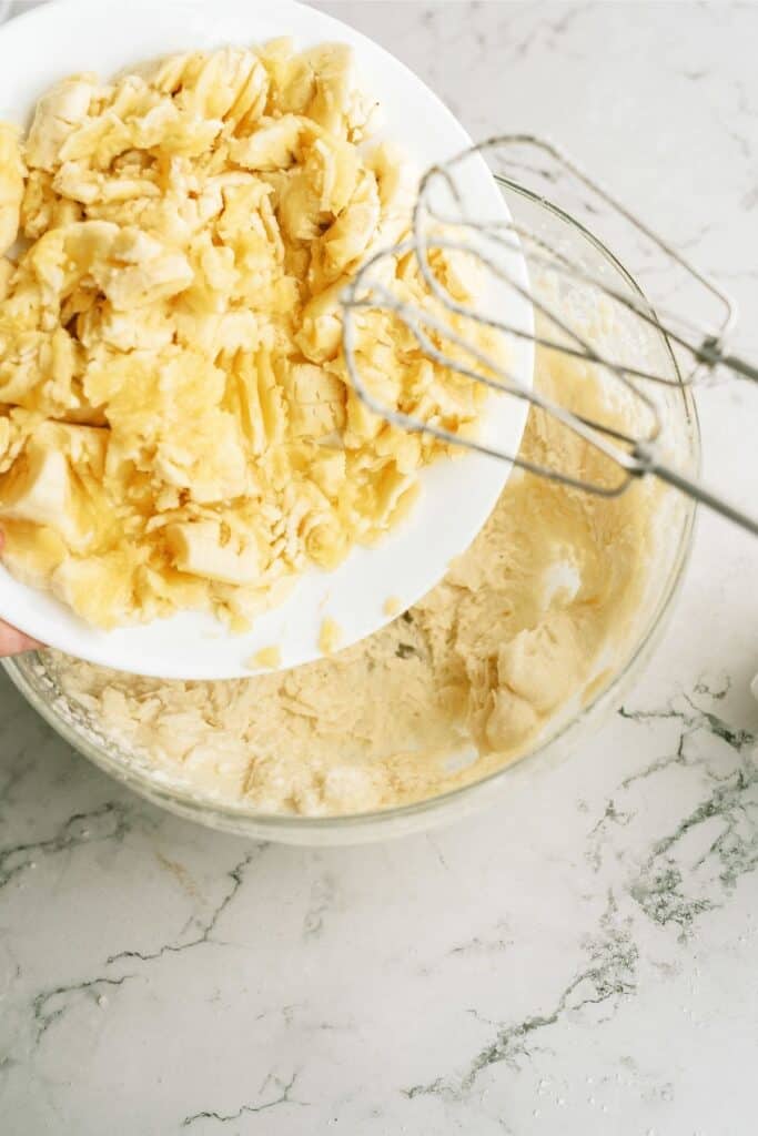 Adding mashed banana to butter and sugar mixture.