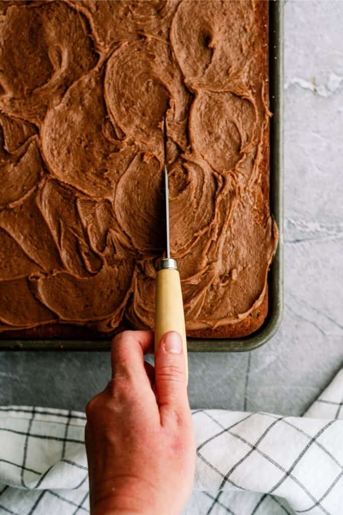 Slicing Chocolate Zucchini Sheet Cake into squares.