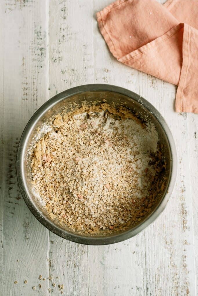 Large metal mixing bowl full of dry ingredients for Peaches and Cream Oatmeal Cookies.