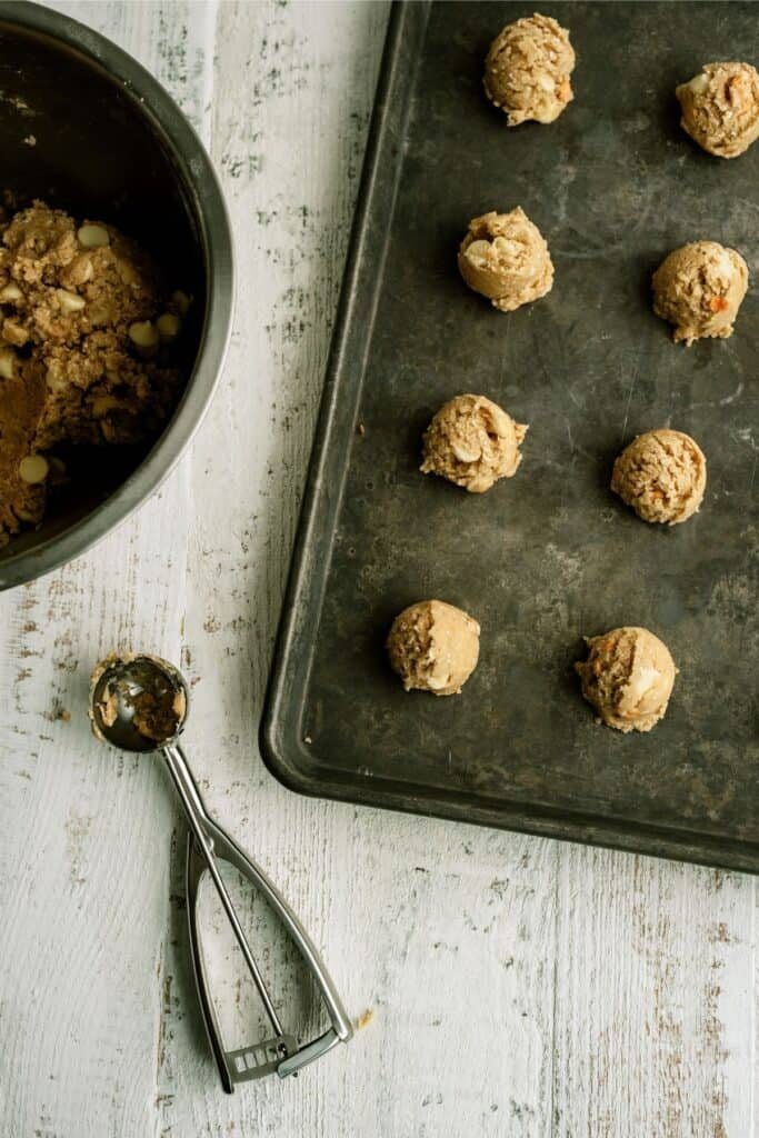 Peaches and Cream Oatmeal Cookies cookie dough balls on a baking sheet with a cookie scoop.