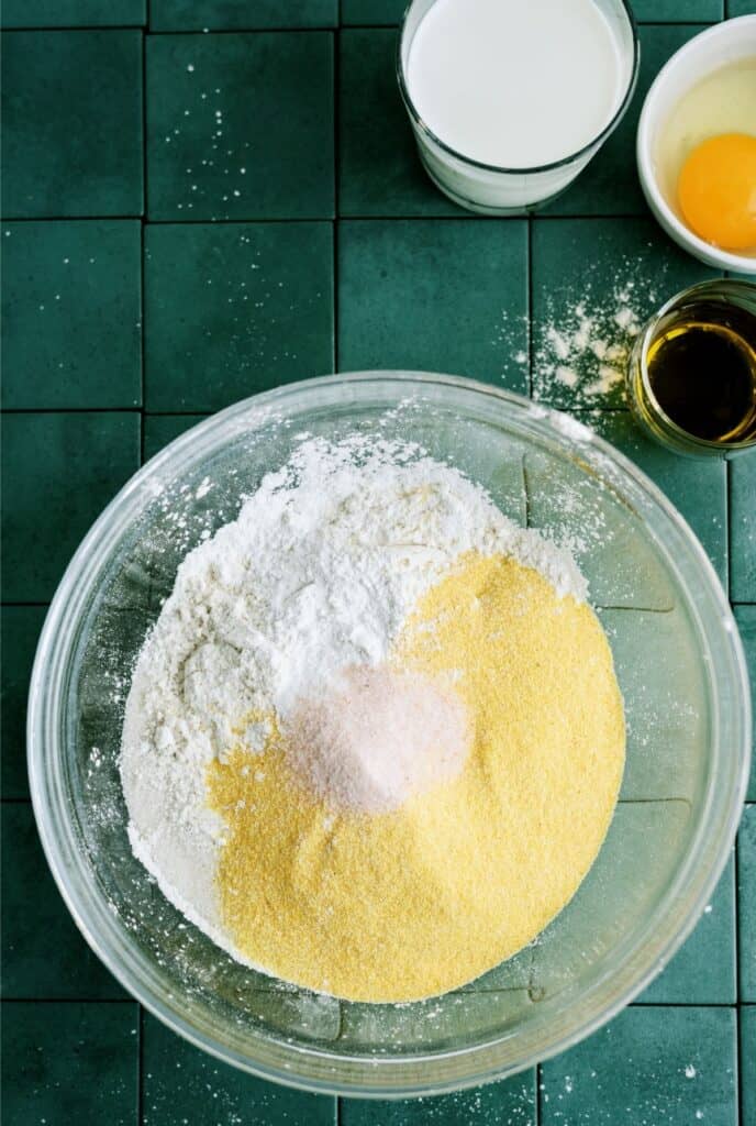 Dry ingredients for Easy Homemade Cornbread in a glass mixing bowl.