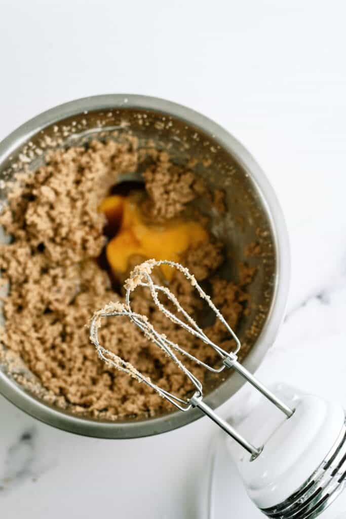 A mixing bowl with cookie dough for Salted Caramel Chocolate Cookies and a hand mixer.