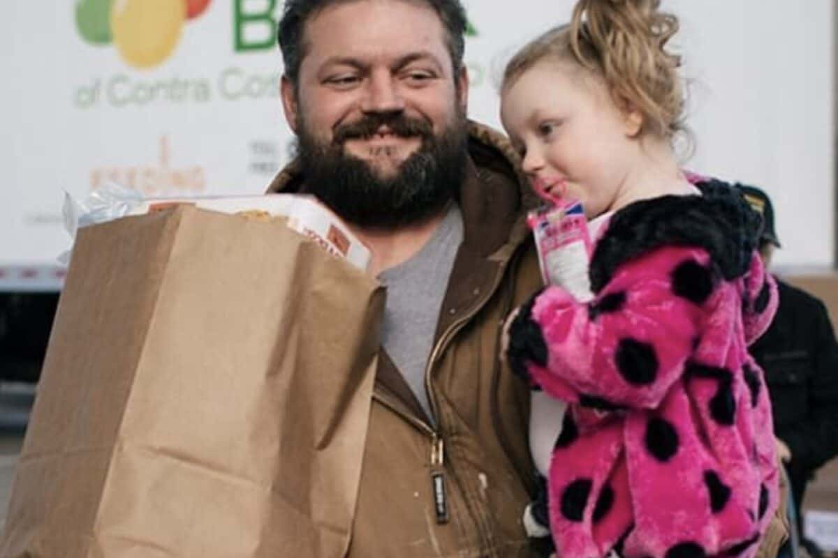 picture of a man holding his daughter and a bag of groceries