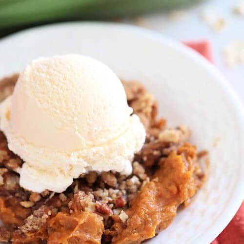 A plate with a serving of pie topped with a scoop of vanilla ice cream.